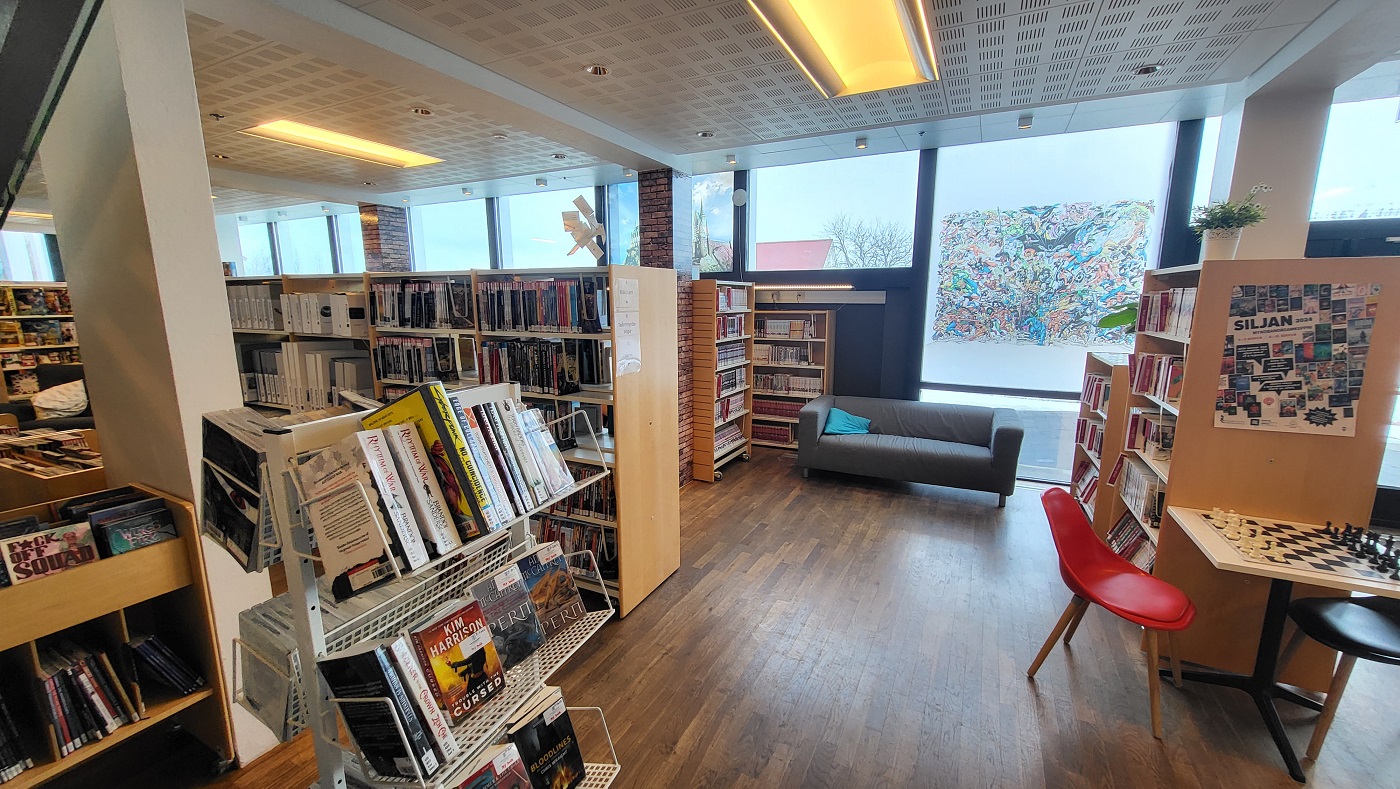 Books in shelves, chess table, chairs and a sofa
