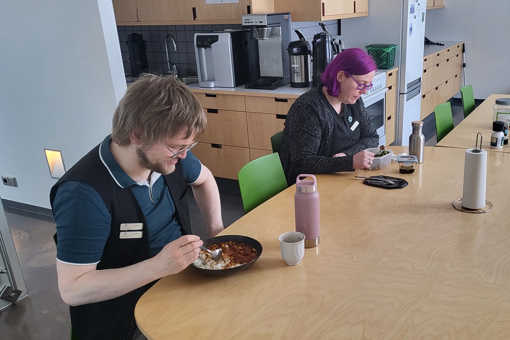 Picture of two people sitting by a table and eating