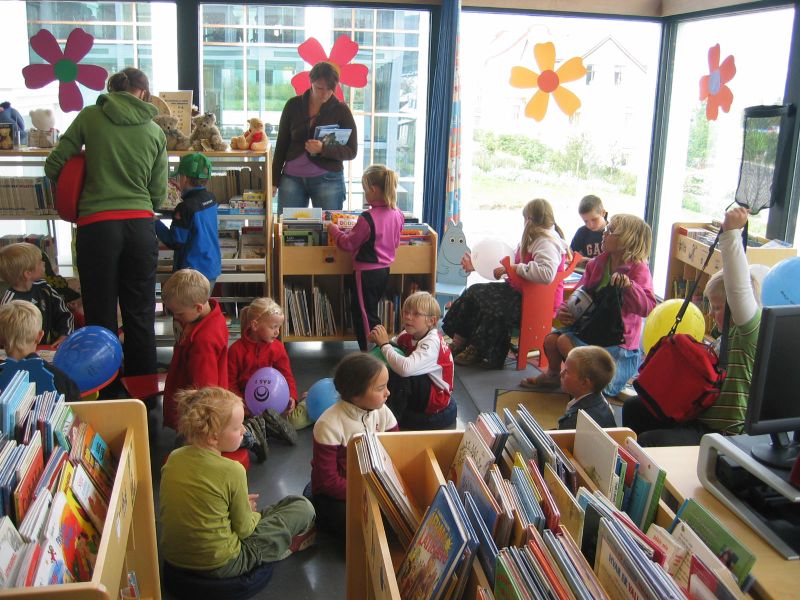 Children's department of a library, children listening and grown ups watching