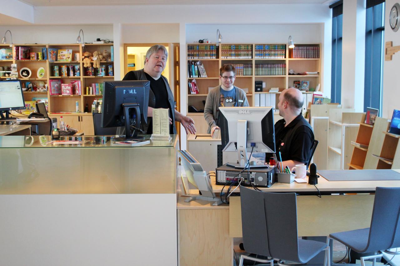 Three staff members behind the main desk and information center at the library